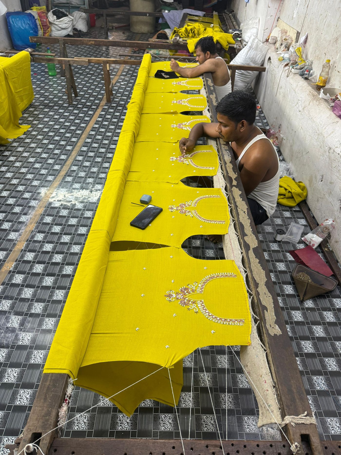 Workers sewing beads into fabric