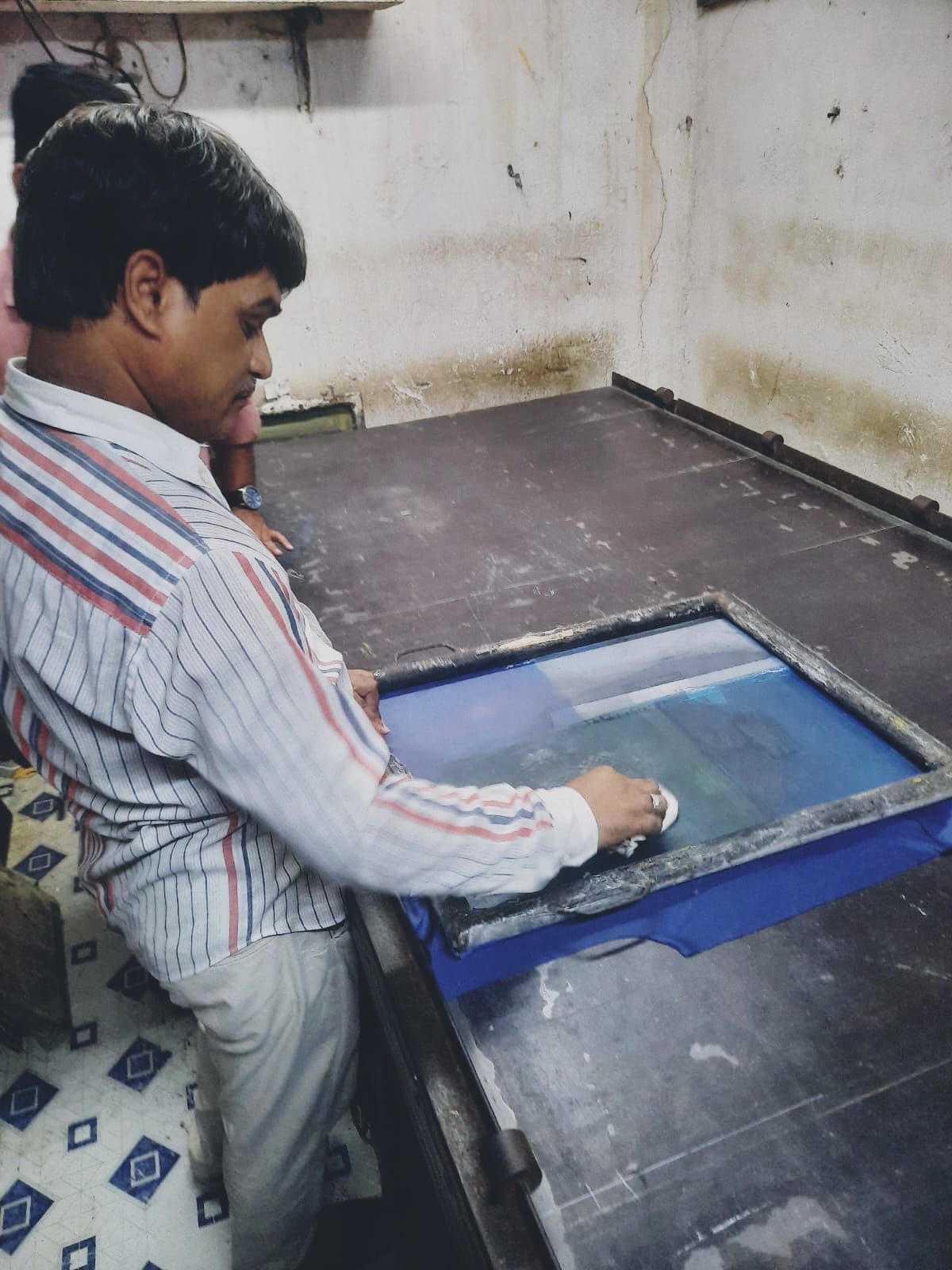 Samsuddin demonstrating the process of printing a t-shirt.