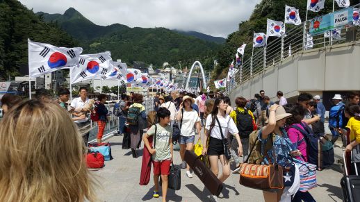 Arrival at Dodong port, lined with Korean national flags and thronged with tourists.